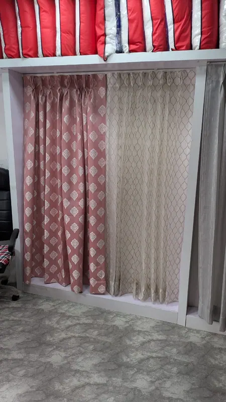 Dusty pink damask and gold trellis pinch-pleat curtain samples on the display rail at the Vartak Nagar showroom