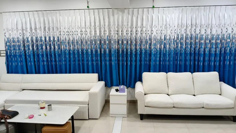 Blue ombre printed curtains fitted behind a cream sofa set in a Thane living room
