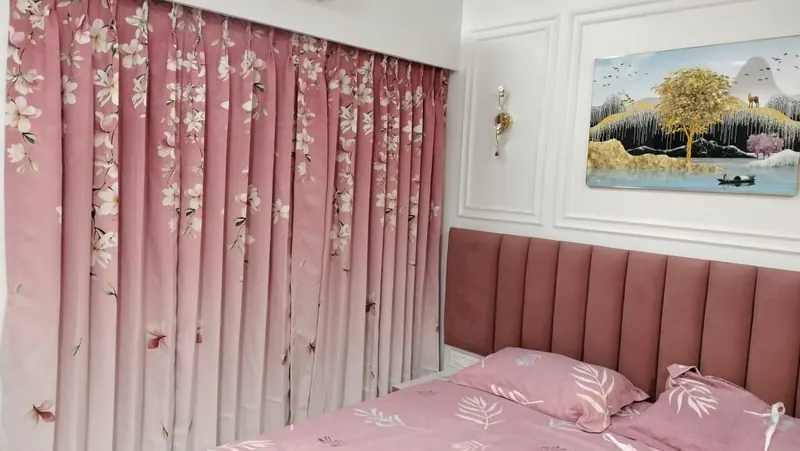 Pink blossom-print curtains matched to a rose velvet headboard in a Thane bedroom