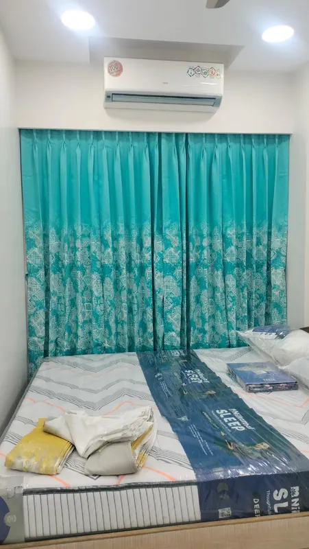 Teal ombre printed pinch-pleat curtains fitted wall-to-wall in a bedroom, with a new mattress below