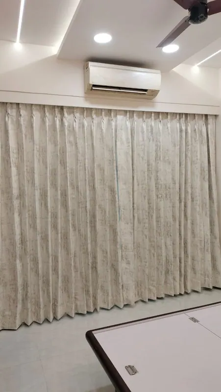 Textured ivory pinch-pleat curtains with a crisp pleat fall, fitted across a living room wall