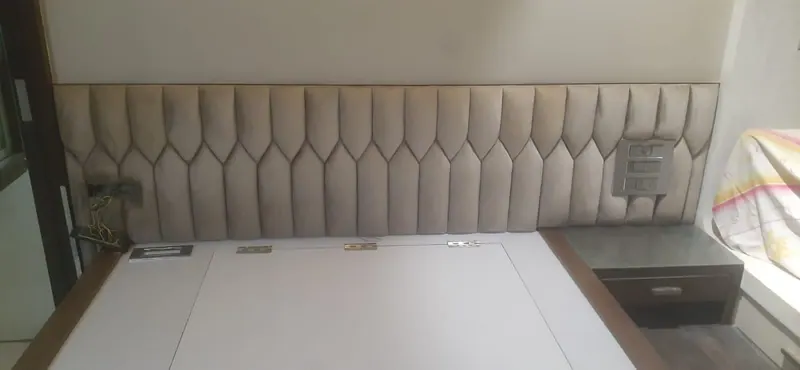 Full-wall beige headboard in elongated hexagon channels, wrapping behind a storage bed