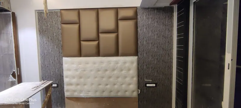 Brown brick-pattern padded wall panels and a white tufted headboard during installation