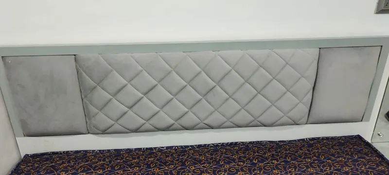 Grey diamond-quilted headboard panel mounted flush to the wall above a bed