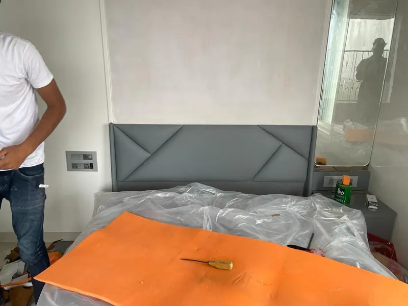 Grey geometric headboard being fitted on site, with the mattress still wrapped