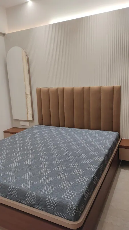 Tan channel-tufted headboard on a storage bed, against a fluted white wall panel