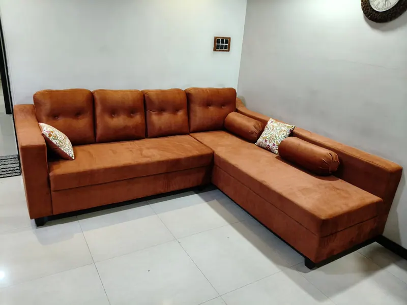 Tan suede L-shape sofa with button-tufted back cushions and bolster pillows