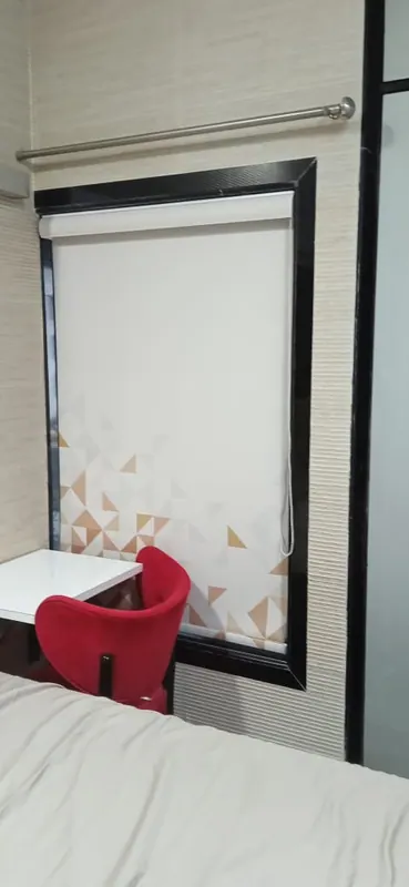 Geometric-print roller blind above a study table, framed in a black laminate window surround