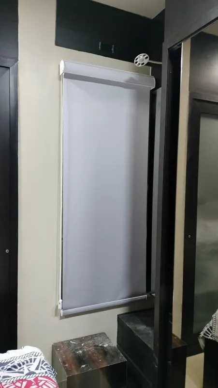 Plain grey blackout roller blind with a chain control, fitted inside a bedroom window recess
