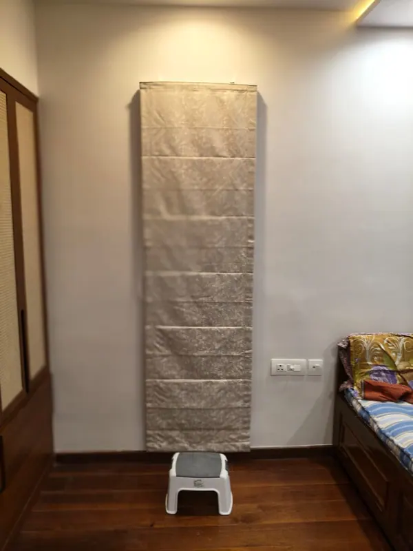 Tall champagne velvet Roman blind with even folds, covering a full-height panel