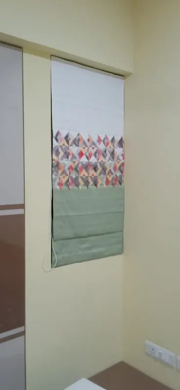 Roman blind in sage green with a geometric diamond band, stitched to order for a narrow window