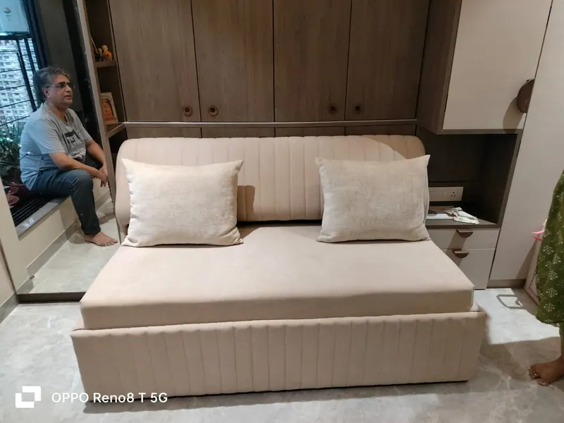 Beige fluted sofa cum bed seated in front of a fitted wardrobe, in sofa position