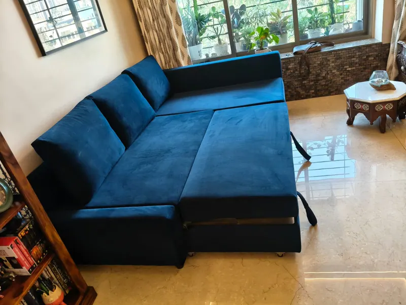 The same navy L-shape sofa cum bed extended into a bed on runners