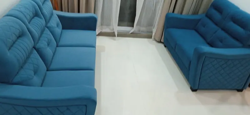 Blue quilted 3+2 sofa set with diamond-stitched side panels in a Thane living room